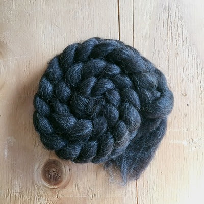 a braid of shetland black wool fibre 100% on a wooden background