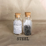 clear small cork bottle with grey sliver stitch markers in