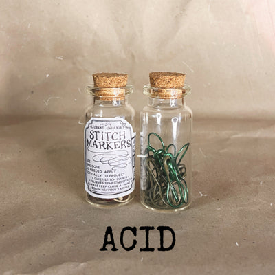 clear small cork bottle with green stitch markers in