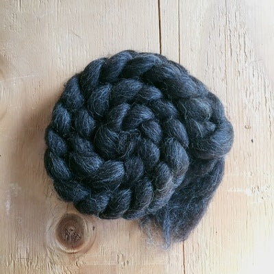 a braid of shetland black wool fibre 100% on a wooden background 