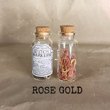 clear small cork bottle with pink gold stitch markers in