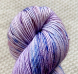 a close up of lilac purple fingering weight yarn in a 100g skein