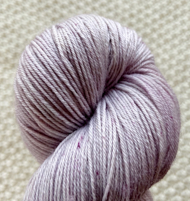 a close up of light pink fingering weight yarn in a 100g skein