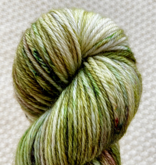  a close up of light green dark green white dk double knit weight yarn in a 100g skein