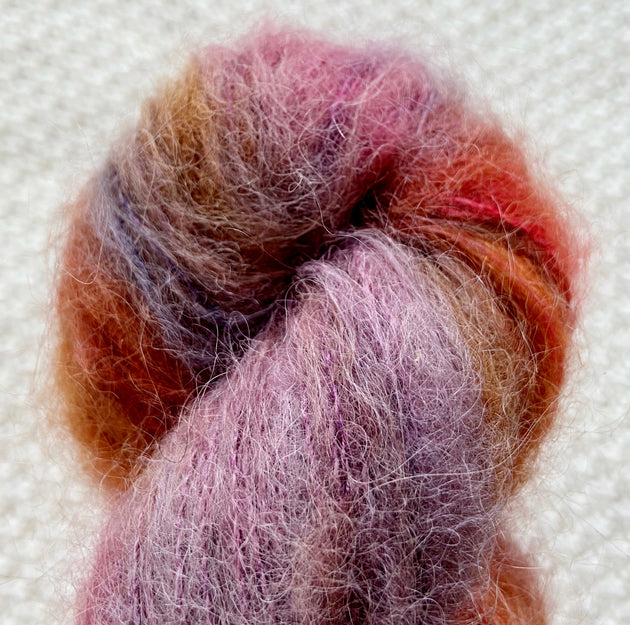a close up of red purple orange lace weight yarn in a 50g skein