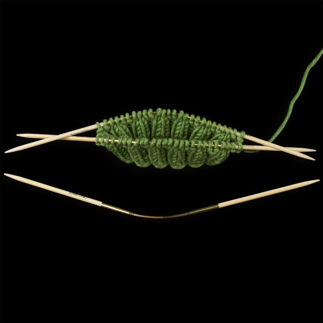bamboo crasytrio needles with the ribbing of a green sock 