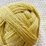 close up of yellow alb lino 100g sock yarn wool and linen on a crocheted white blanket