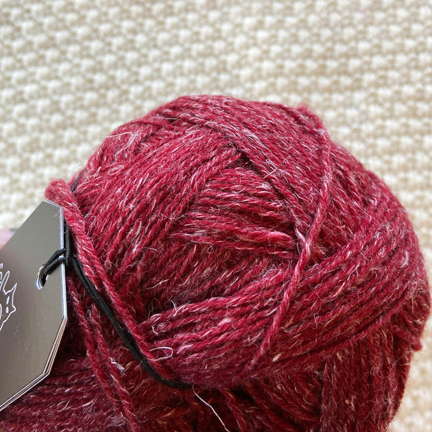 close up of red  alb lino 100g sock yarn wool and linen on a crocheted white blanket 