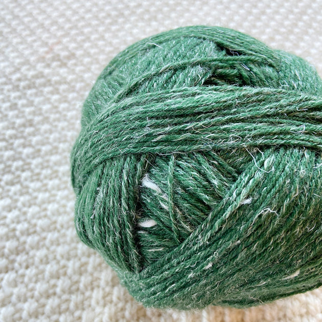 close up green alb lino 100g sock yarn wool and linen on a crocheted white blanket