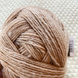 close up of light brown alb lino 100g sock yarn wool and linen on a crocheted white blanket