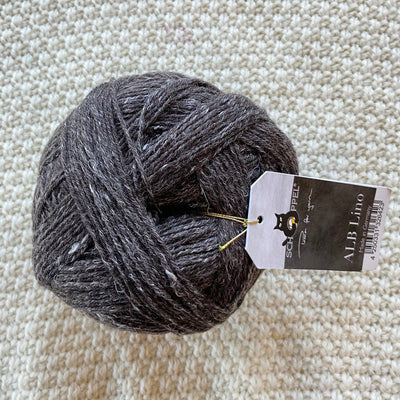 black alb lino 100g sock yarn wool and linen on a crocheted white blanket