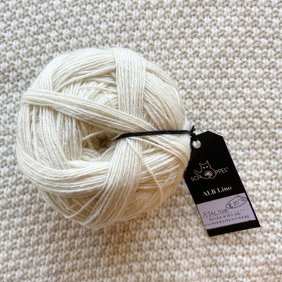 white alb lino 100g sock yarn wool and linen on a crocheted white blanket 