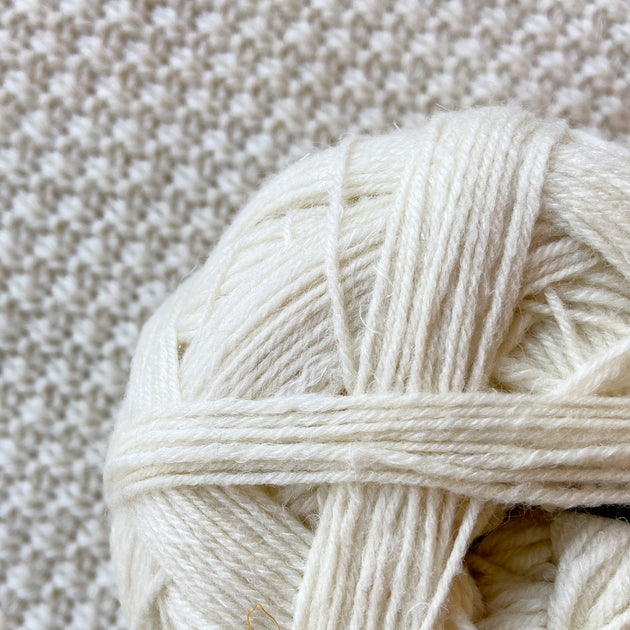 close up of white alb lino 100g sock yarn wool and linen on a crocheted white blanket  
