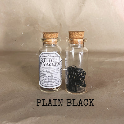 clear small cork bottle with black stitch markers in