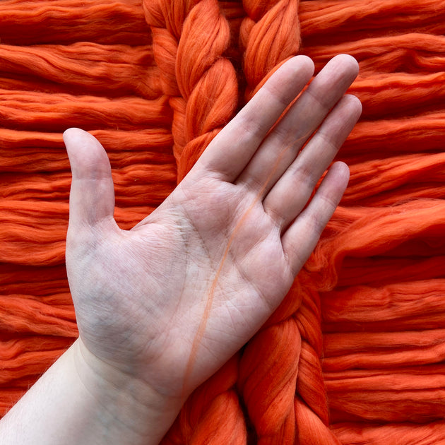 a white woman holding a bit of fibre in her hand orange eco nylon biodegradable spinning fibre braid 