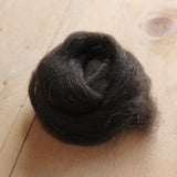 a small amount of black welsh spinning fibre on a wooden floor 