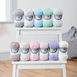 eleven balls of 4ply yarn on white steps grey white blue green pale multi colour brown cream pink purple 