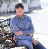 a white man with brown hair wearing a knitted jumper maid of blue white aran weight skein  machine washable for knitting crocheting and weaving sat at the beach