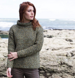 a white woman with ginger hair wearing a knitted jumper made of green orange purple white yarn 