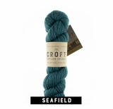teal green blue aran weight skein machine washable for knitting crocheting and weaving with the croft tag on the side