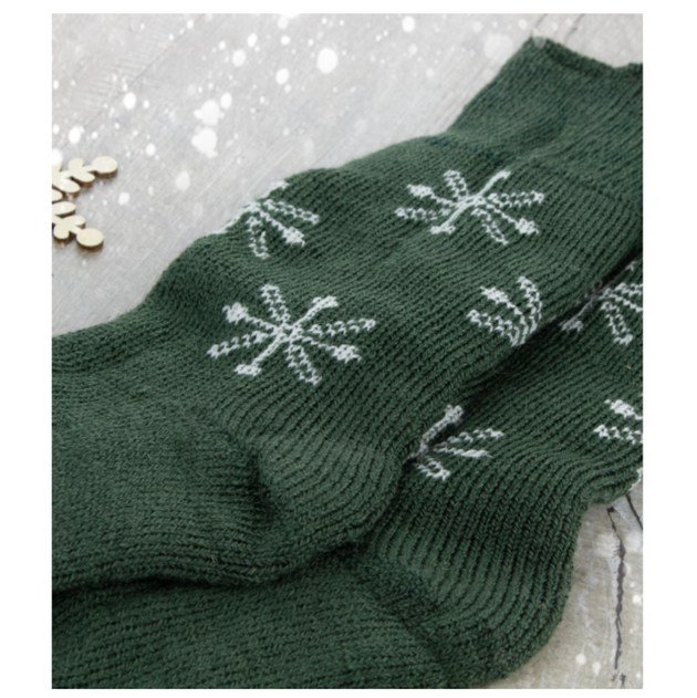 a close up of west yorkshire spinners christmas socks a pair of green socks with white snowflakes 