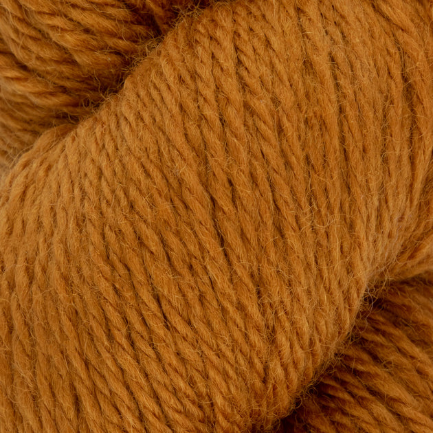 close up of orange mustard aran weight skein machine washable for knitting crocheting and weaving
