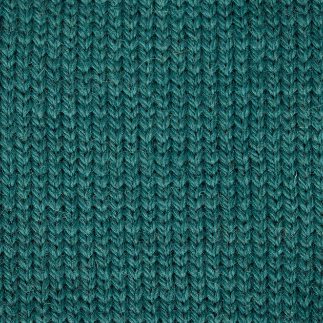a close up of a knitted swatch teal green blue aran weight skein machine washable for knitting crocheting and weaving